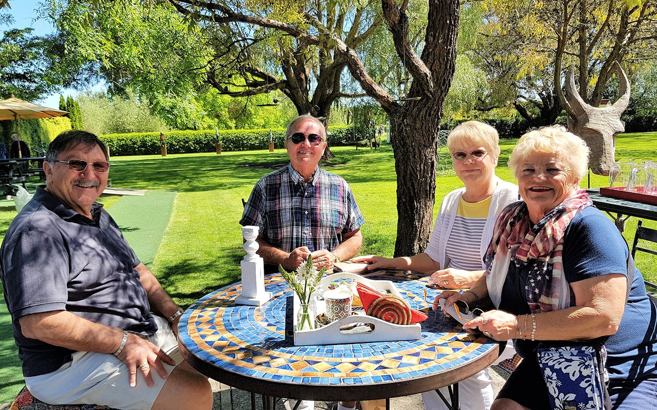 Group enjoying outdoor dining in a garden setting on the Grand Day Out in Hawkes Bay Tour.