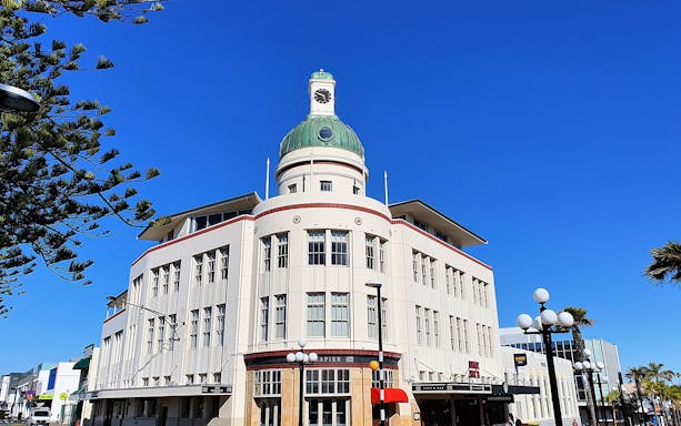 Art Deco building with clock tower in Napier, Hawkes Bay, under clear blue sky.