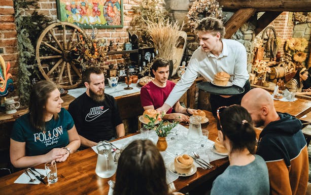 Guests enjoying traditional Polish bread served by a local guide in a rustic restaurant setting.