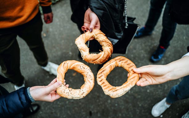 Hands holding traditional Polish obwarzanek bread during a food tour.
