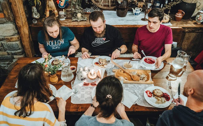 People enjoying traditional Polish dishes at a communal table during a food tour.