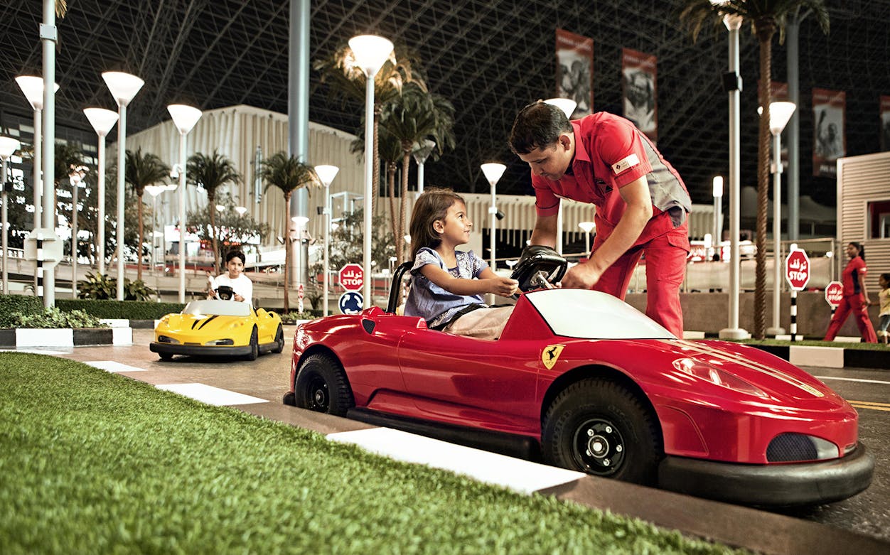 Child driving a mini Ferrari at Ferrari World Abu Dhabi with an instructor.