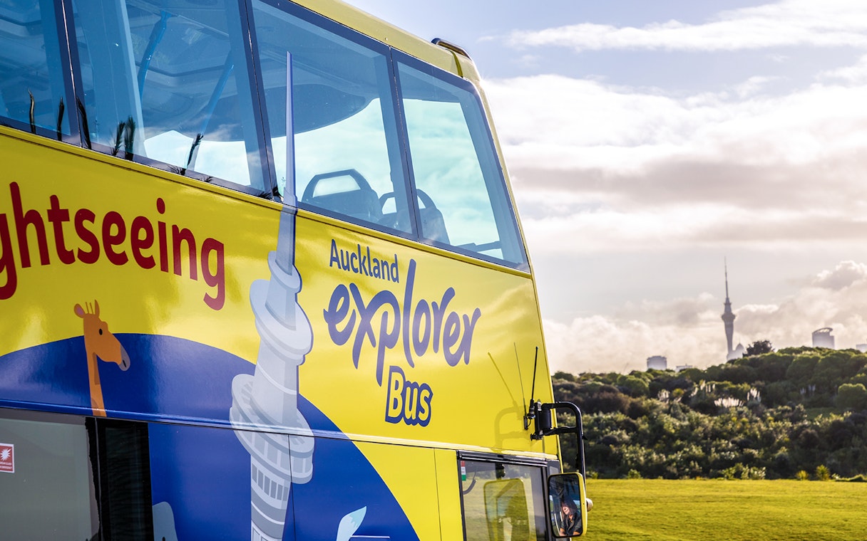 Auckland Explorer Bus with Sky Tower in the background on a city tour.