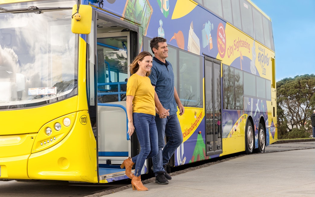 Couple exiting Auckland Explorer Bus on hop-on-hop-off city tour.