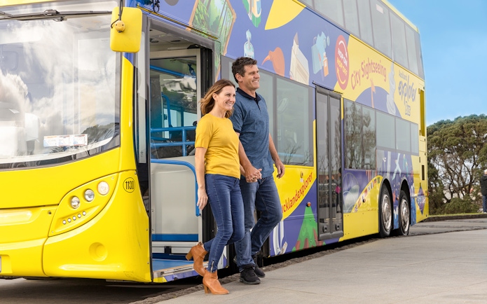 Couple exiting Auckland Explorer Bus on hop-on-hop-off city tour.