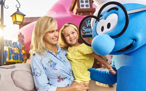 Mother and daughter meeting Brainy Smurf at a theme park.