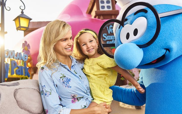 Mother and daughter meeting Brainy Smurf at a theme park.