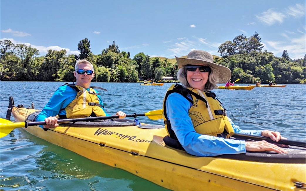 Kayakers on Lake Rotoiti during guided tour with Manupirua Hot Pools in background.