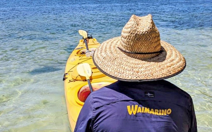 Person in straw hat with kayak on Lake Rotoiti during guided tour.