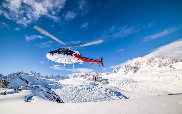 Helicopter flying over snowy mountains on Neve Discoverer Tour from Franz Josef.