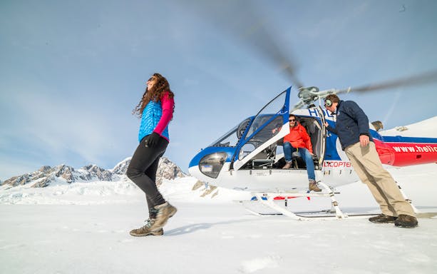 Helicopter landing on snow with tourists at Franz Josef Glacier, New Zealand.