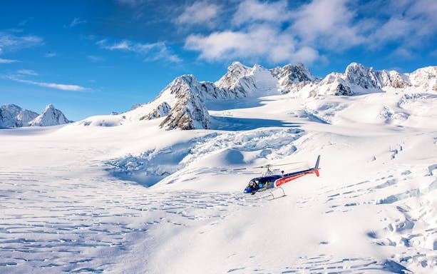 Helicopter flying over snowy mountains on Neve Discoverer Tour from Franz Josef.