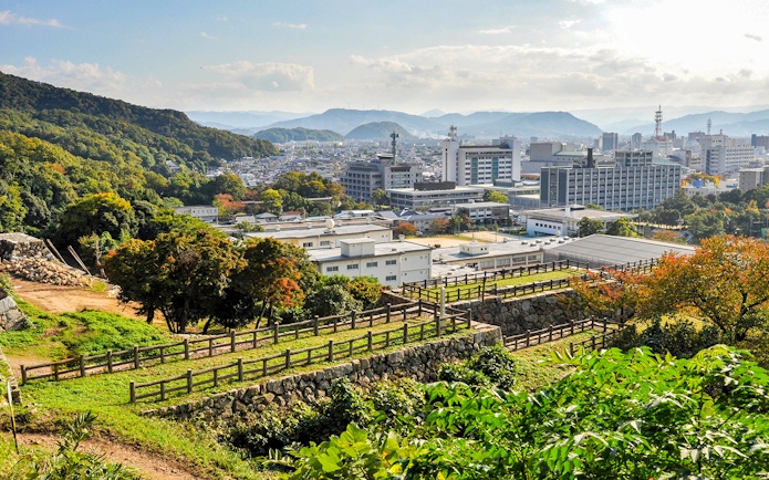 View of Okayama cityscape with surrounding hills, seen from a historic site, Japan.