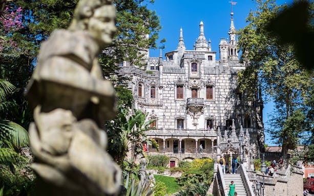 Quinta da Regaleira in Sintra with tourists exploring gardens and architecture.