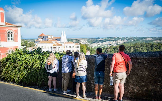Tourists enjoying a view of Sintra's landscape and architecture during a guided Jeep safari tour.