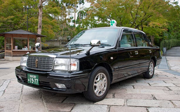 Kyoto taxi tour passing Kinkaku-ji Temple with cherry blossoms in view.