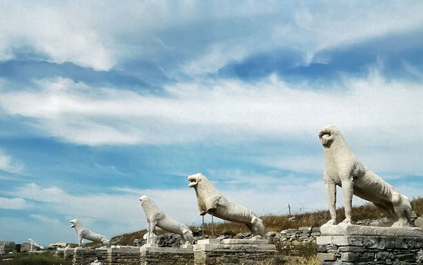 Lion statues on the Terrace of the Lions, Delos, Greece, under a blue sky.