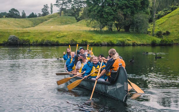Guided canoe tour on a river near Tauranga with participants paddling.
