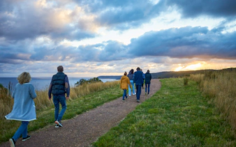 Group walking along a coastal path at sunset during the Dusk Discovery Tour.