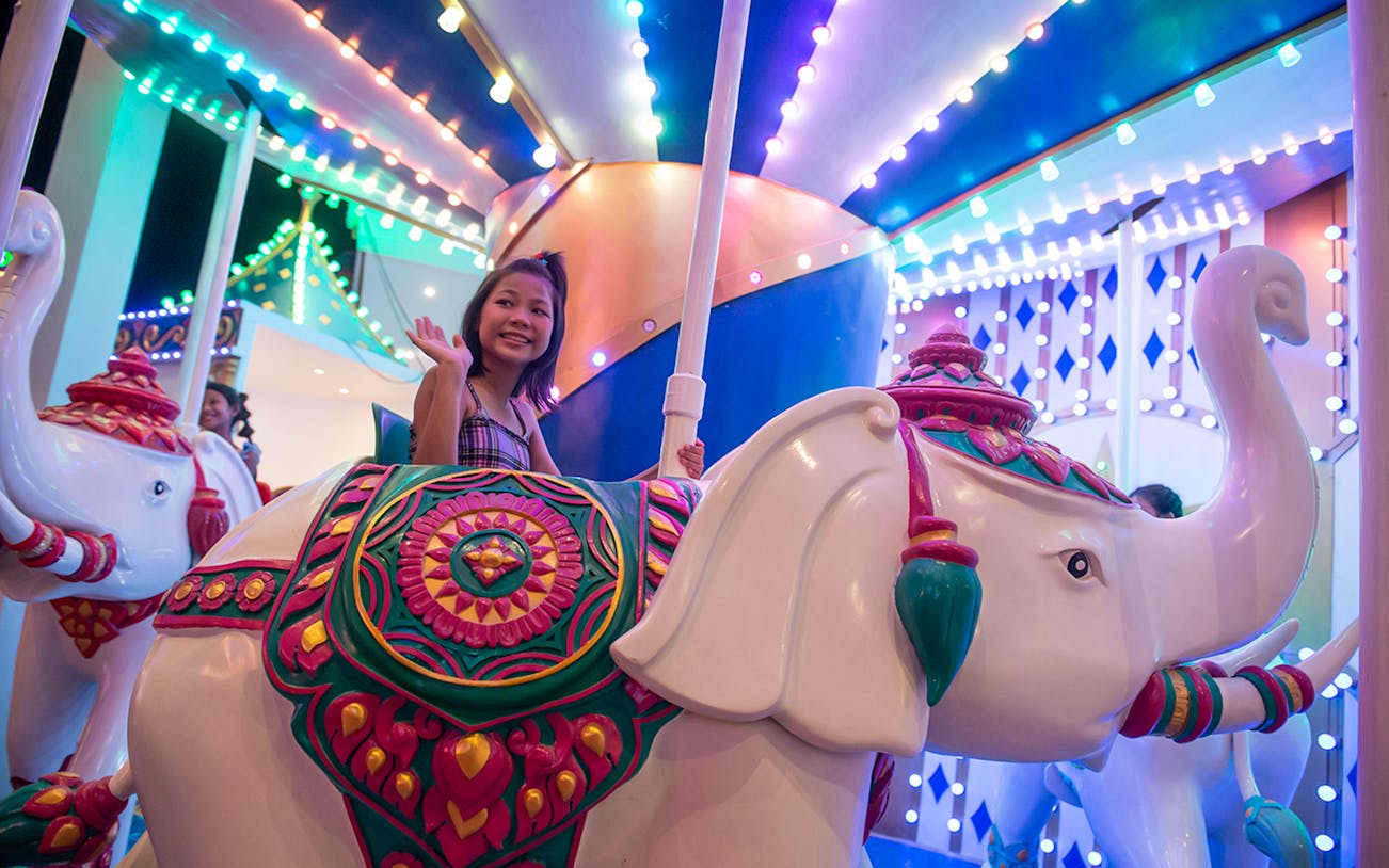 Child riding elephant carousel at Carnival Magic Park, Phuket.