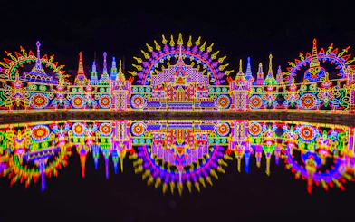 Colorful neon lights display at Carnival Magic Park, Phuket, reflecting in water.