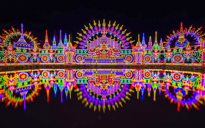 Colorful neon lights display at Carnival Magic Park, Phuket, reflecting in water.