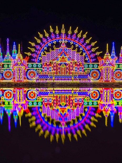 Colorful neon lights display at Carnival Magic Park, Phuket, reflecting in water.