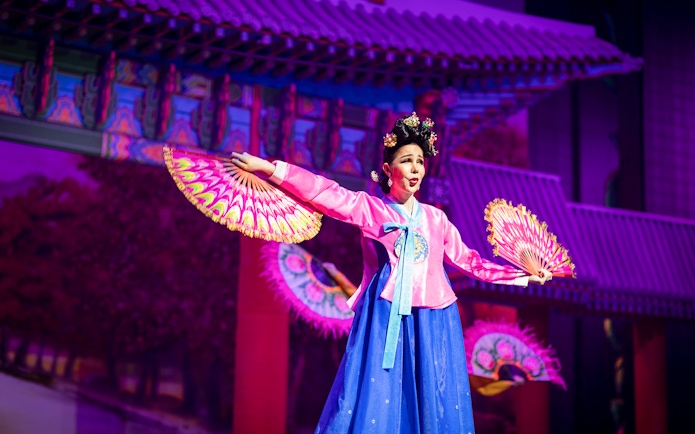 Performer in traditional costume with fans at Alcazar Cabaret Show.