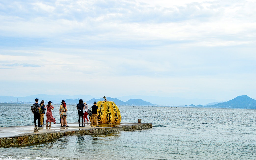 Tourists viewing Yayoi Kusama's pumpkin sculpture on Naoshima Island, Japan.