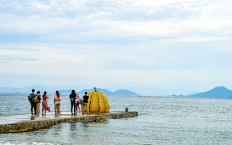 Tourists viewing Yayoi Kusama's pumpkin sculpture on Naoshima Island, Japan.