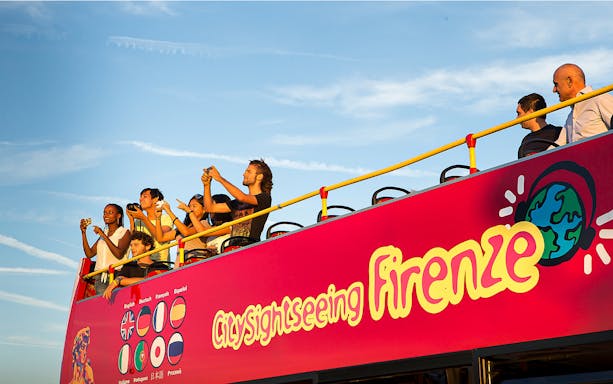 Tourists on Florence hop-on hop-off bus taking photos of city landmarks.