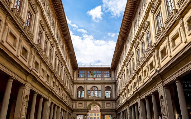 Uffizi Gallery courtyard in Florence, Italy, with architectural details and blue sky.