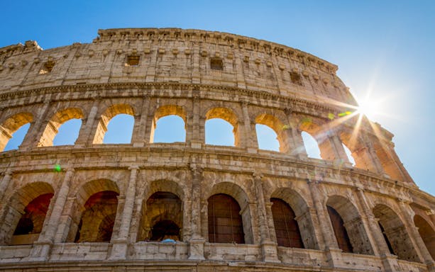 Colosseum in Rome with sunlight streaming through arches.