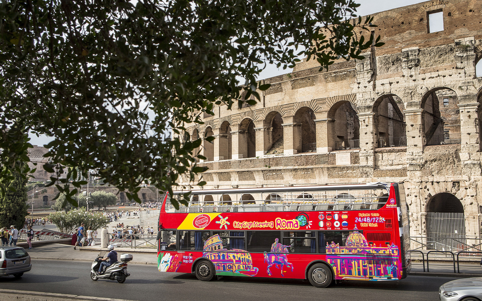 Red hop-on hop-off tour bus in front of the Colosseum, Rome.