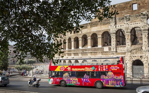 Red hop-on hop-off tour bus near the Colosseum in Rome.