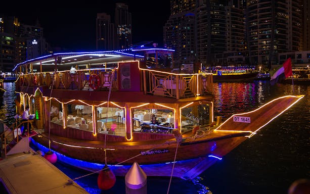 Dhow boat illuminated at night on Dubai Creek, set for a dinner cruise.