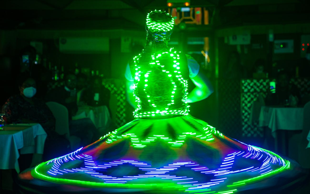 Performer in LED costume spinning during Dhow Dinner Cruise on Dubai Creek.