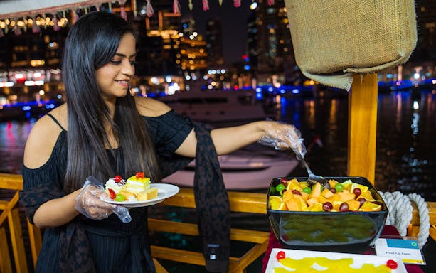 Woman serving dessert on Dhow Dinner Cruise, Dubai Creek.