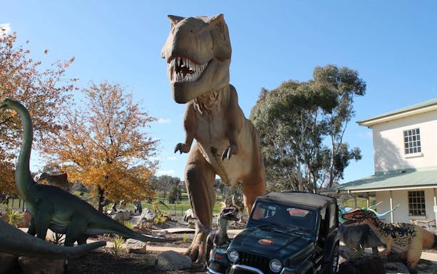 Tyrannosaurus rex statue at National Dinosaur Museum entrance with other dinosaur models.