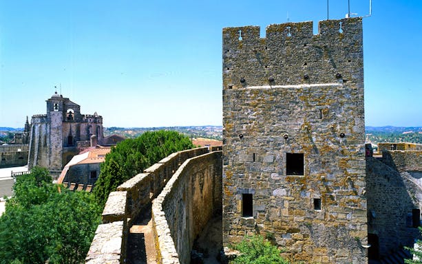 Convent of Christ stone walls and tower in Lisbon, Portugal, with scenic landscape.