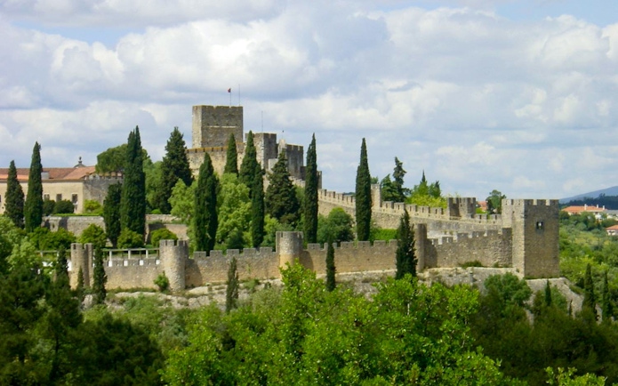 Convent of Christ in Lisbon with medieval walls and lush greenery.