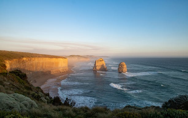 Twelve Apostles rock formations along the Great Ocean Road coastline at sunset.