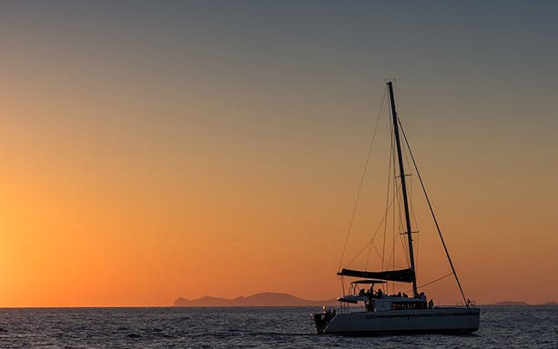 Sailboat cruising at sunset with distant islands, part of a private sunset dinner cruise experience.
