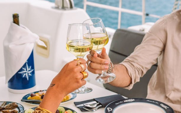 Toasting with wine glasses on a private sunset cruise dinner.