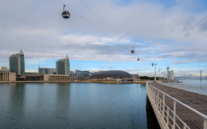 Telecabine cable cars over Tagus River in Lisbon, Portugal, with cityscape in the background.