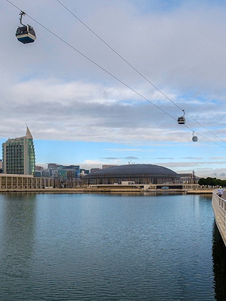 Telecabine cable cars over Tagus River in Lisbon, Portugal, with cityscape in the background.