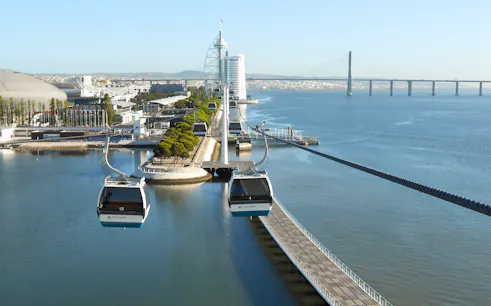 Telecabine cable cars over Tagus River in Lisbon with cityscape and bridge in view.