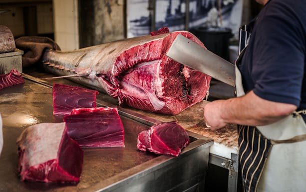Butcher preparing fresh tuna at ancient market in Syracuse.