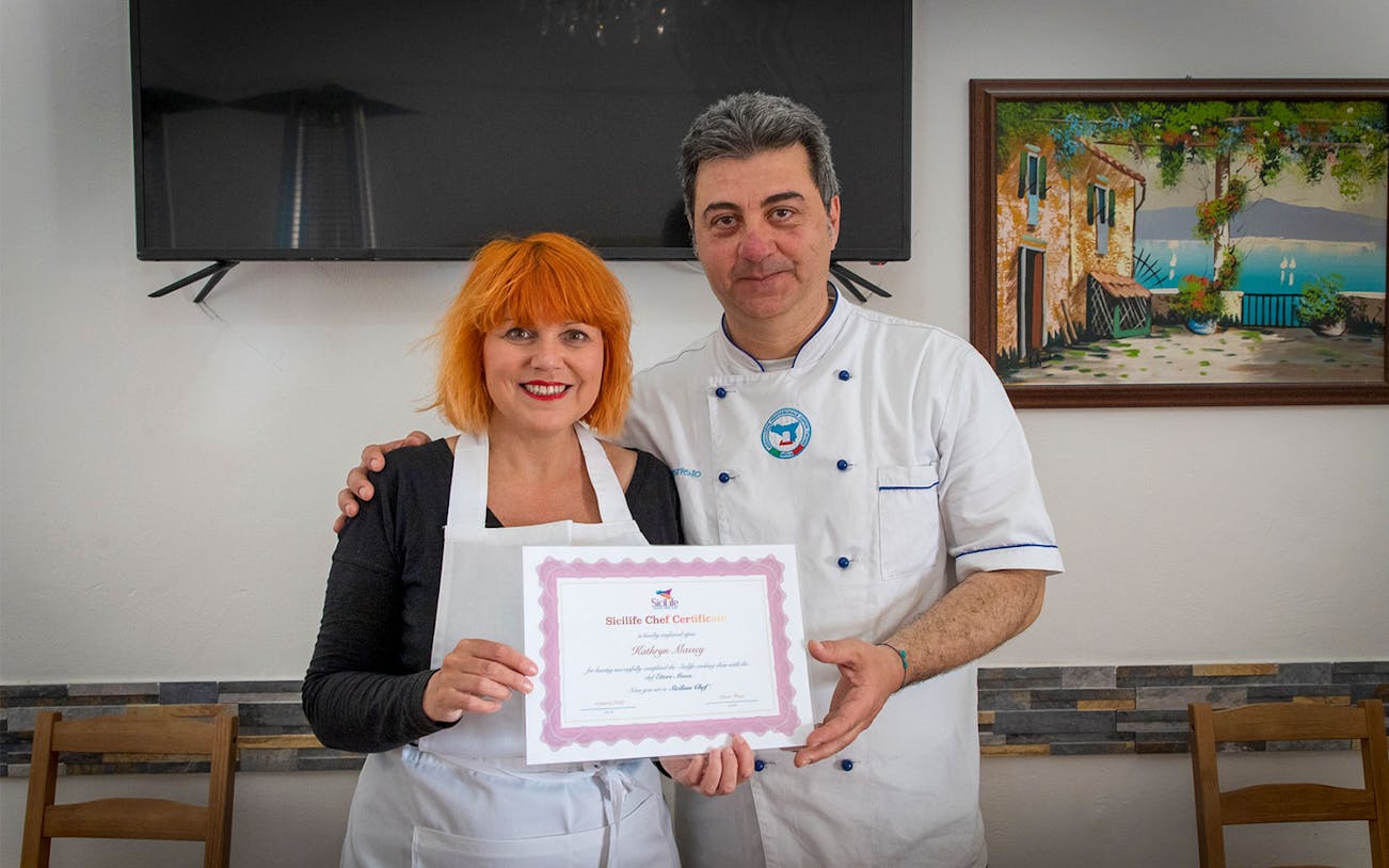 Chef presenting certificate to participant in Syracuse cooking class.