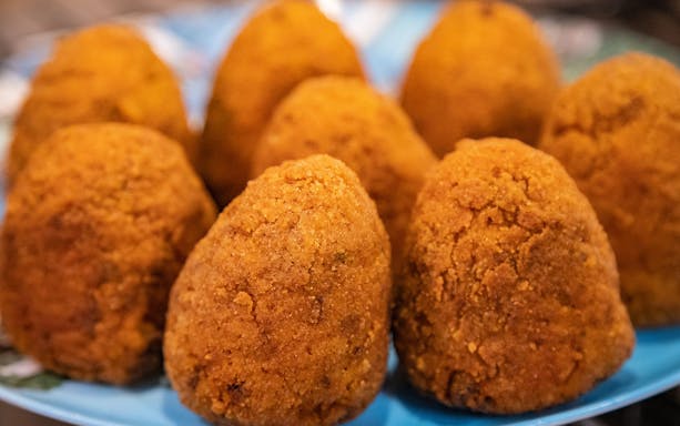 Arancini served on a blue plate during a cooking class in Syracuse.